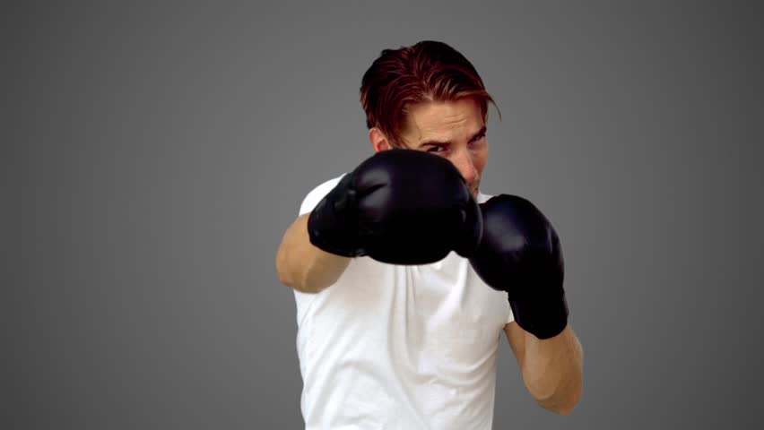 Sportsman boxing in front of the camera in slow motion on grey background
