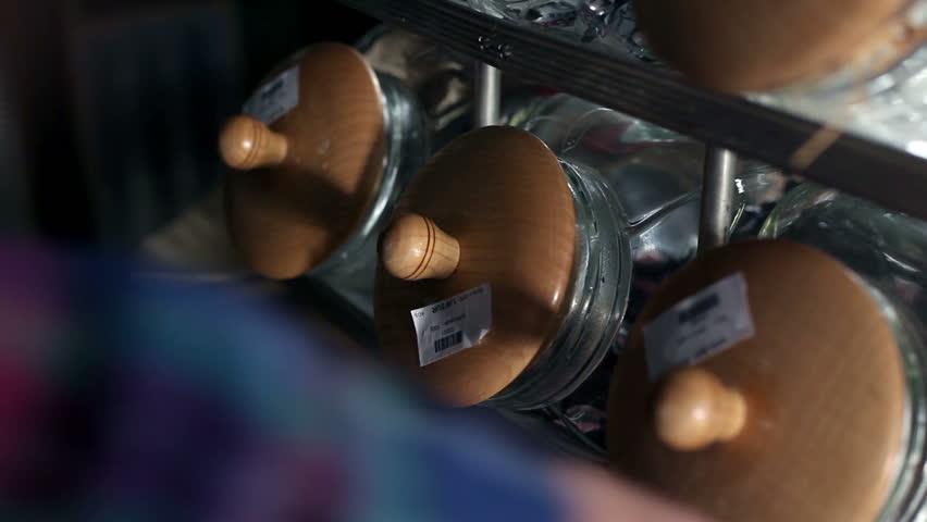 Close up shot of a seller who is taking candies out of the big glass jar