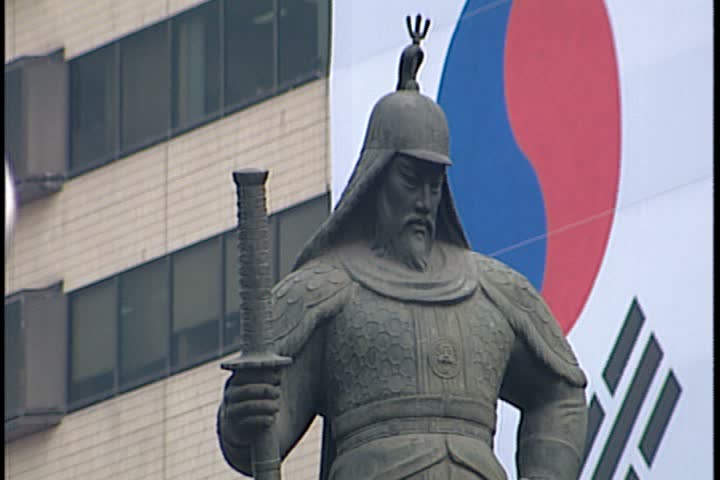 SEOUL - FEBRUARY 26, 1997: Day time b-roll of Jung-gu section of Seoul; CU face of bronze statue of Admiral Yi Sun Sin. Giant Korean flag hanging on building in background.