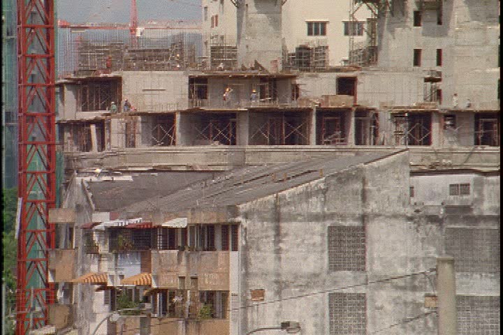 KUALA LUMPUR - CIRCA OCTOBER 1999: WS older building, tilt up to WS of skyline showing the tops of tall cranes, spires and the Petronas Towers.