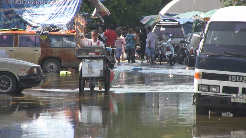 Bangkok, Thailand - October 2011: A squid seller pushes his stall through flood waters on his way to work.