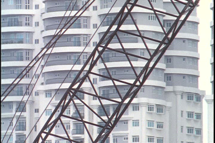 KUALA LUMPUR - OCTOBER 25, 1999: Kuala Lumpur construction site; CU crane rigging is lowered in foreground, with modern residential apartment tower behind.