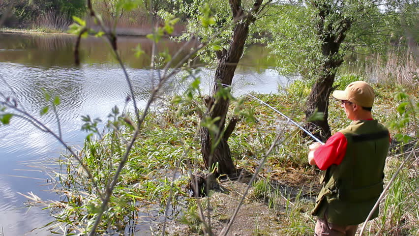 sport fisherman fishing on a river bank with fishing rod,video clip ; Fisherman