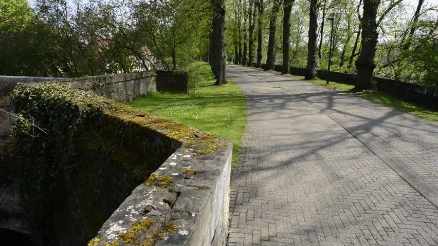 Bruges, Belgium in spring - panoramic footage of the canal, old houses, blooming tree close to the Minnewater park.