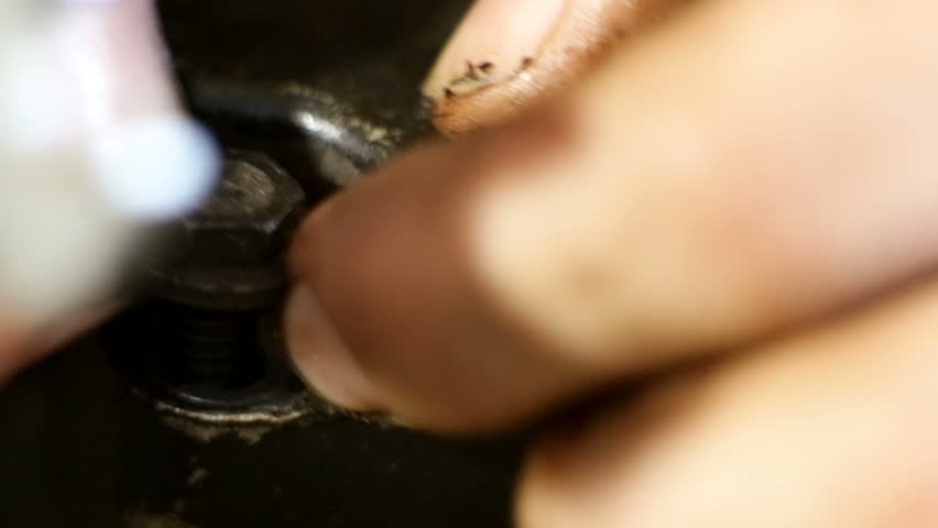 Young man cleaning a dirty engine of a mini motor. A lot of oil. Working in workshop on the floor. Unscrewing parts of the motor.