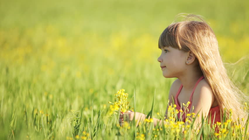 Girl lying on the grass and smelling flowers
