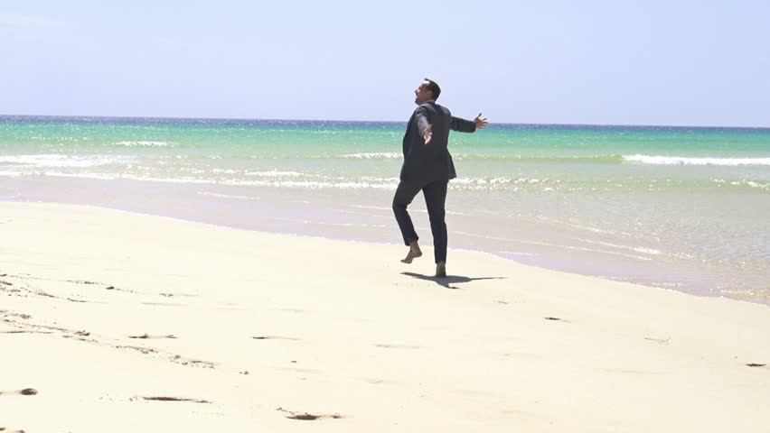 Excited businessman running on the beach, super slow motion, shot at 240fps
