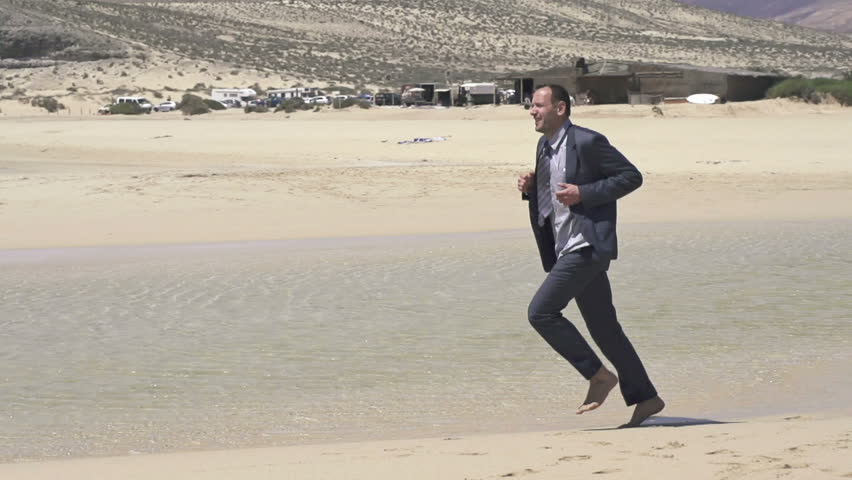 Happy businessman jogging on exotic beach
