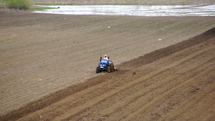 HEILONGJIANG PROVINCE, CHINA - CIRCA MAY 2013: Tractor plowing the field (04). Chinese farmer on a small tractor plowing a field in spring day. Tracking shot. North China, Heilongjiang Province, May 2013.