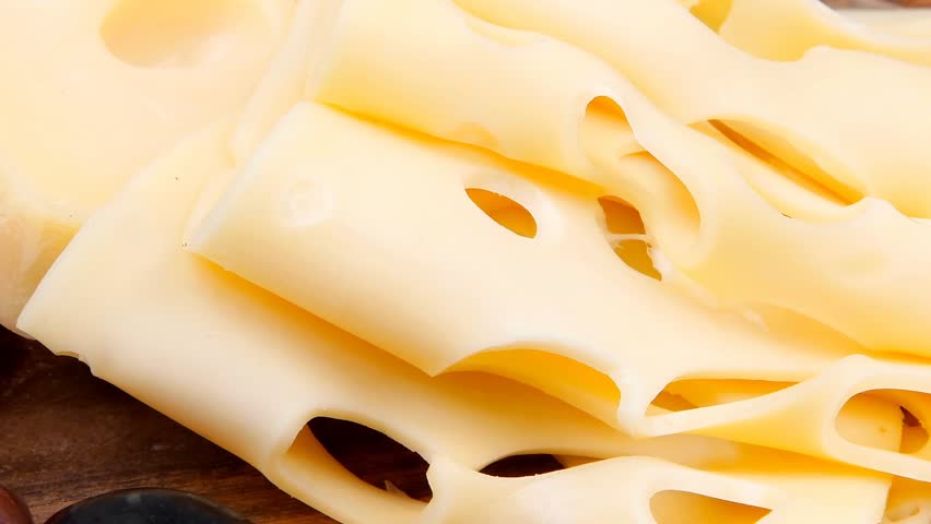 gold swiss cheese sliced on wooden platter with olives and tomato 1920x1080 intro motion slow hidef hd