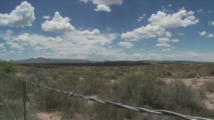 Time lapse of clouds over New Mexico desert, with barbed wire in foreground.