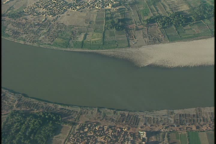 Aerial shot in Khartoum, Sudan. Looking directly down at murky Nile River bordered by small houses on either side.