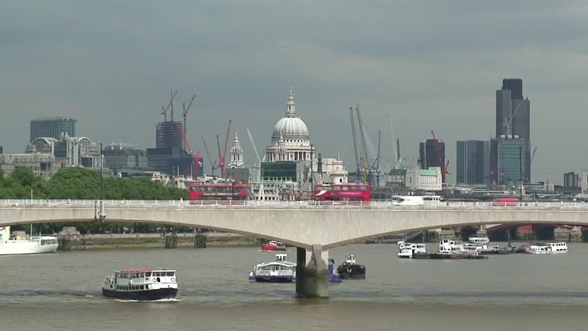 Close up of Waterloo Bridge over River Thames in London with St PaulÃÂ´s Cathedral, red double decker buses and ferries crossing