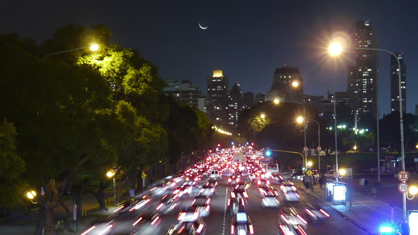 Traffic in the city. Avenue Time-Lapse, Night. Moon going down. Heavy traffic / jam / flowing with blurred motion. Dusk. Crane out / zoom.