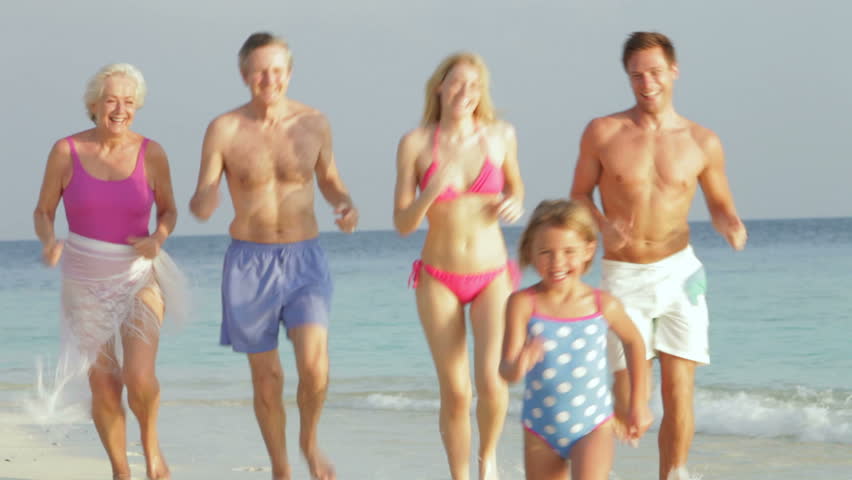 Multi Generation Family Having Fun In Sea On Beach Holiday
