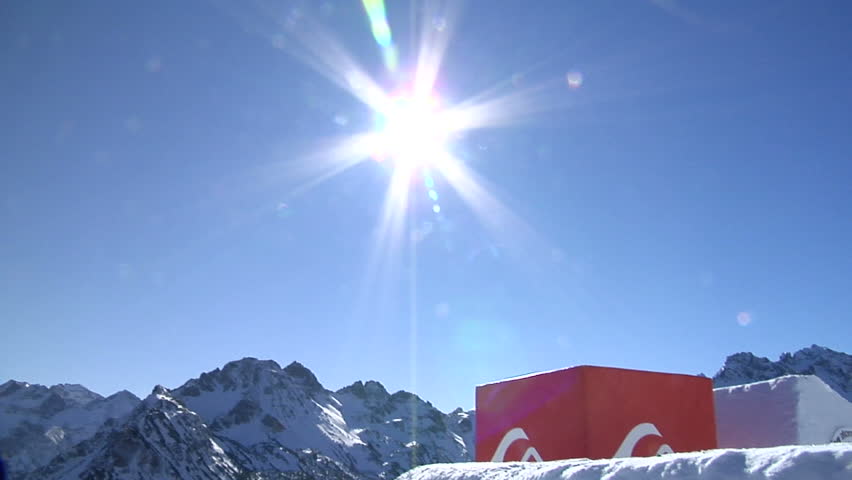 snowboarder jumps through sun in the blue sky