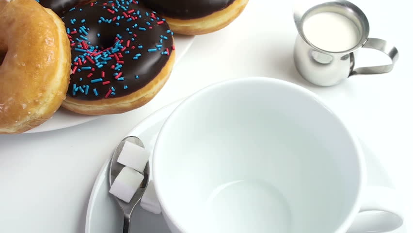 1920x1080 Coffee poured to wash down glazed, chocolate donuts with sprinkles.