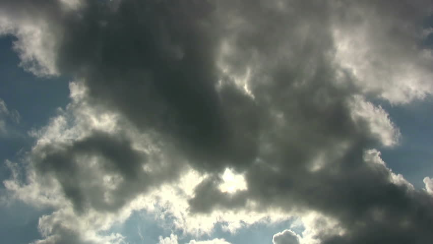 Time lapse of dark, moving clouds on a blue sky sky with penetrating sun.
