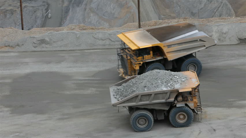 Two large dump trucks passing Kennecott Copper Mine central Utah. Open pit. Worlds largest open pit copper mine.  Ophir Mountains Salt Lake City. Tons of rock and minerals driving slow on dirt road.