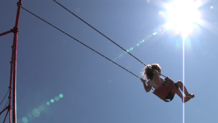 A young girl swings on a swing set.