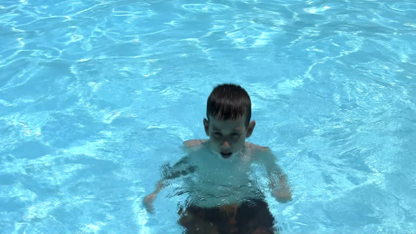 Boy spitting water in a pool