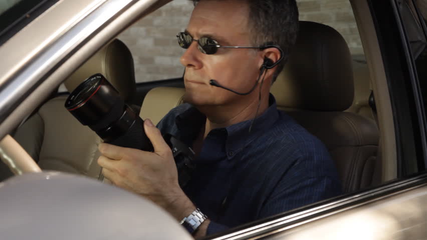 An undercover agent puts down his camera and speaks into a small earpiece he is wearing.