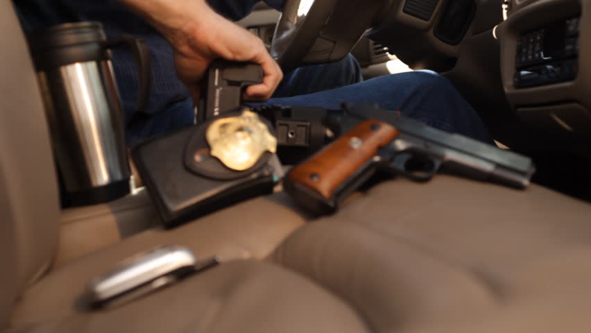 A police detective sitting in his car with a camera taking pictures of something or someone.