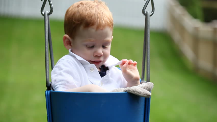 Cute baby boy sitting in swing