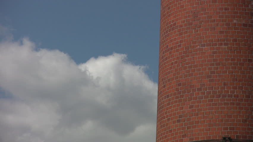 Industrial brick chimney. Clouds pass by.