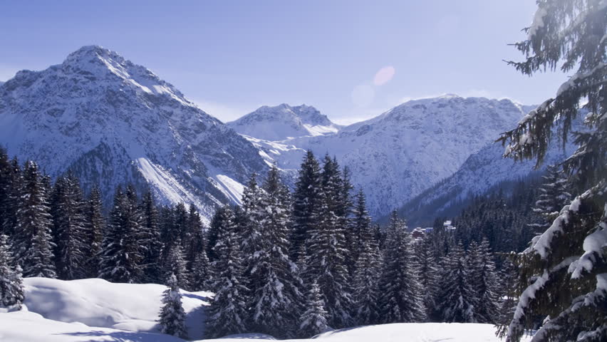 Moving winter postcard: A beautiful scene taken in the middle of the Swiss alps. Snow covered fir trees, dramatic mountains. (time-lapse)