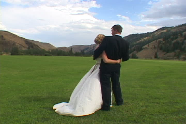 Unrecognizable Bride and Groom hold each other in Washington State Valley after ceremony.