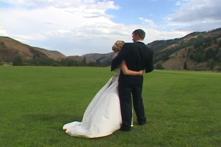 Unrecognizable Bride and Groom hold each other in Washington State Valley after ceremony.