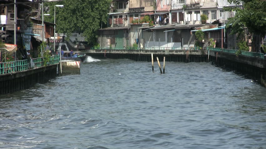 A wooden canal boat slowly arrives at its stop along the canal in Bangkok, Thailand.