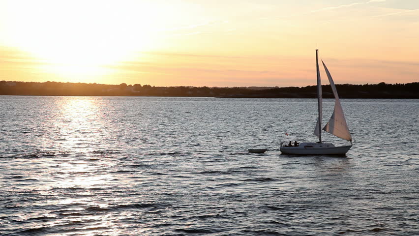 Small set sailing past setting sun