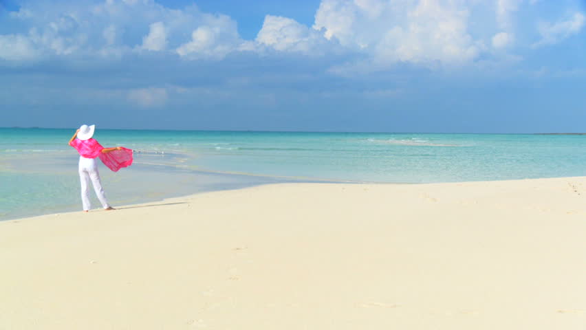 Elegant young female on a beautiful white sandy beach looking at aquamarine waters 60 FPS 210009