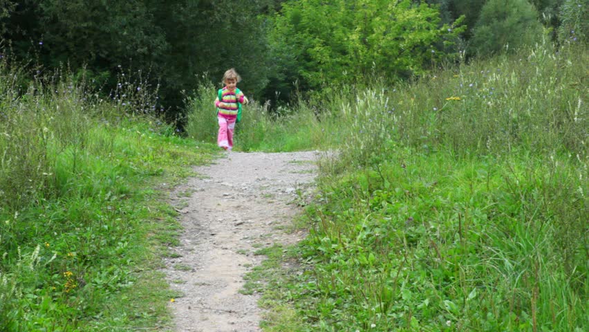 little girl with rucksack running in park to camera 