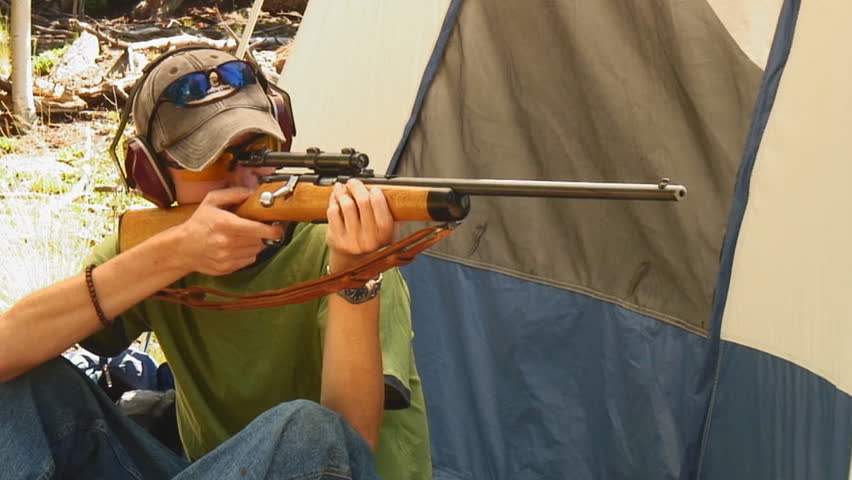young man shoots vintage .22 caliber rifle from sitting position