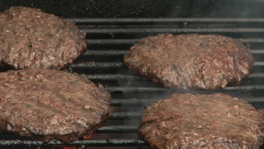 Four Burgers Cooking on Grill with Flame