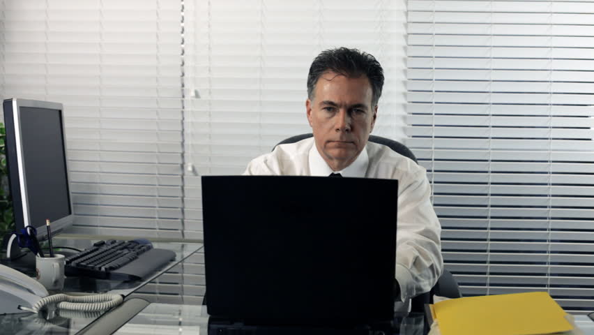 A man stops working, leans back in his chair and starts to daydream about retirement.