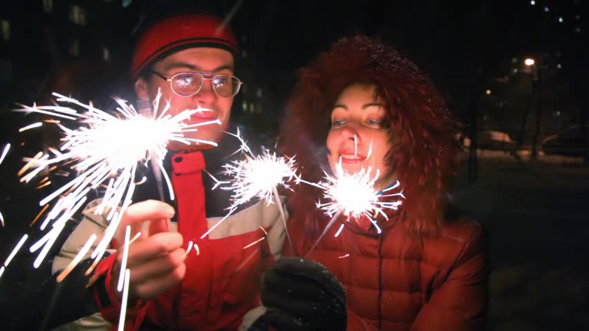 young woman and man with sparklers, night outdoor 