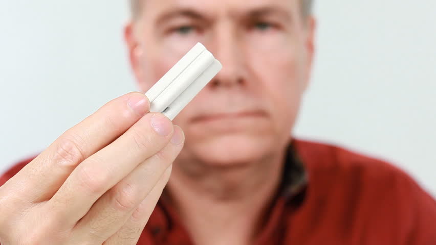 A man resolved to quit smoking cuts up a bunch of cigarettes with a pair of scissors.