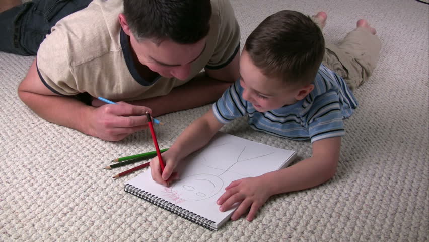 Father and son coloring together on the floor