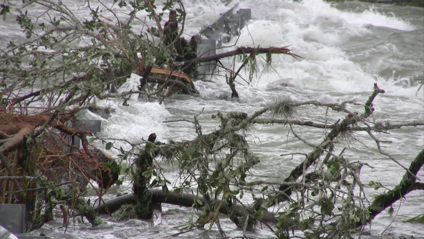 Video zoom out of flooded road in south Texas. Road and guard rail disappearing into swollen river. 