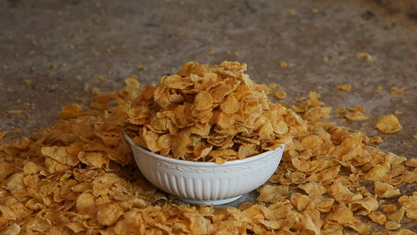 Cereal Corn Flake cereal being poured into a bowl Reverse motion from bowl out and away. Breakfast meal. Pour into white bowl. Bowl sitting on polished granite counter.