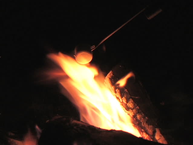 CLOSE-UP OF ROASTING A MARSHMALLOW OVER A FIRE