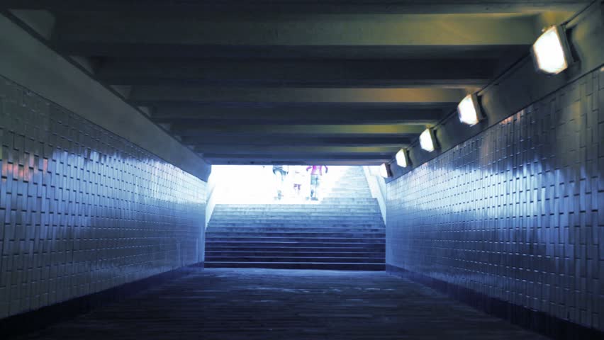 family of three persons running in underground passage from camera, joined hands 