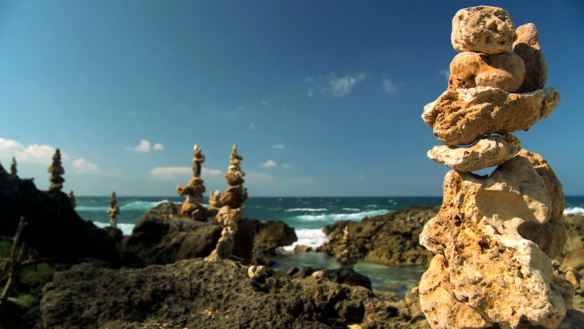 Small rocks symmetrically balanced in peaceful location on shoreline with ocean backdrop