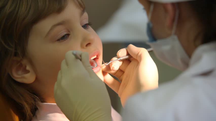 female dentist treats teeth of little girl 
