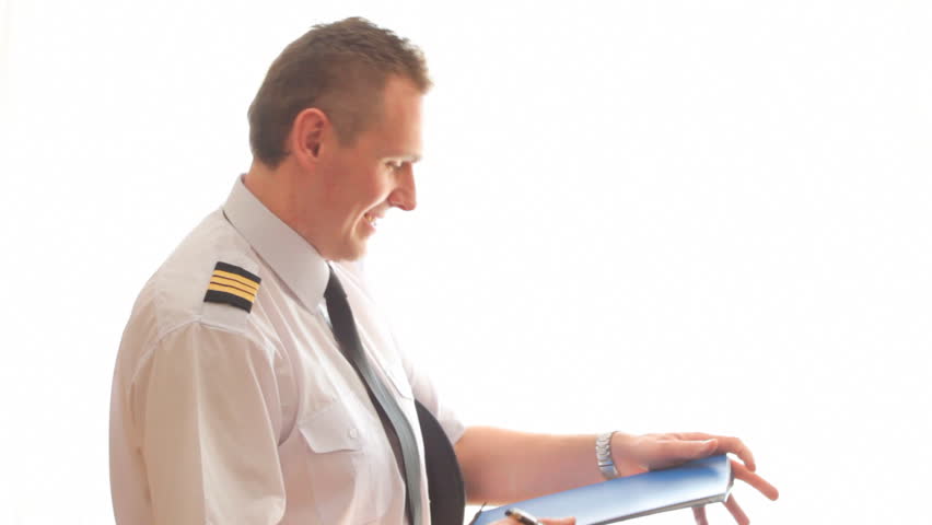 Airline pilot wearing hat, shirt with epaulets and tie filling in and checking papers flight plan, log book and weather forecast.