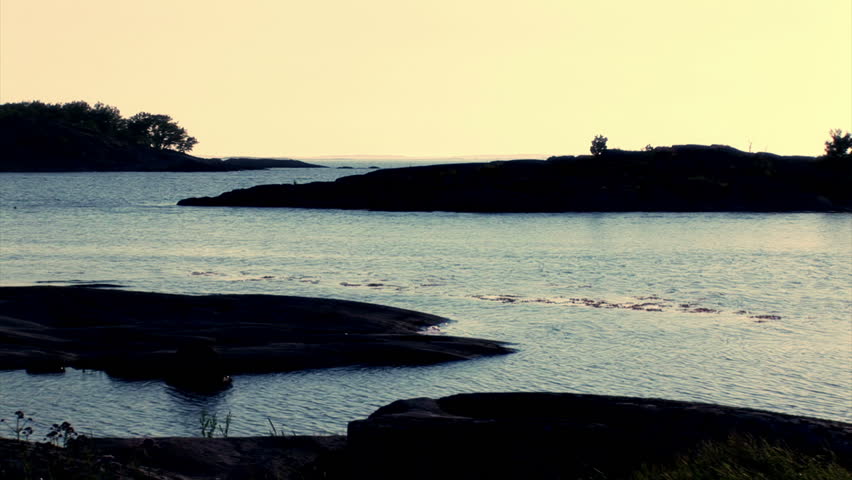 Young man walking on cliff. Sitting down looking at the sunset.